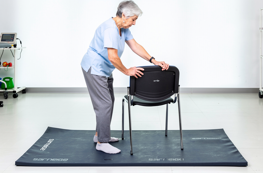 Personne âgée pratiquant des exercices d'équilibre sur un tapis de rééducation.
