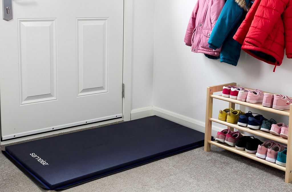 Tapis de gym bleu marine plié près de l'entrée d'une maison d'assistante maternelle.