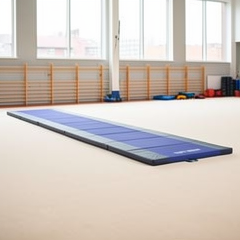 Tapis de gymnastique bleu sur praticable à ressorts dans une salle d'entraînement lumineuse et spacieuse.