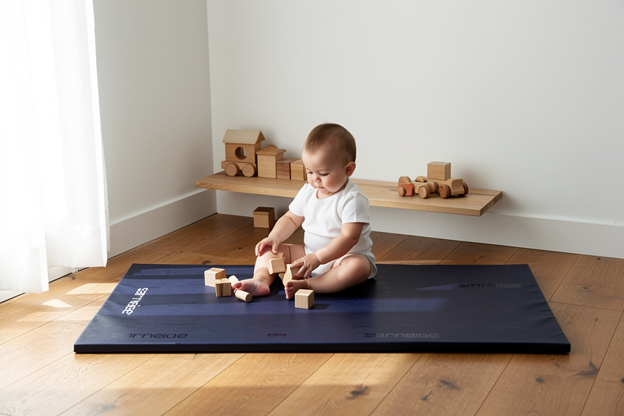 Tapis de motricité bleu dans un coin de crèche aménagé selon la pédagogie Pikler